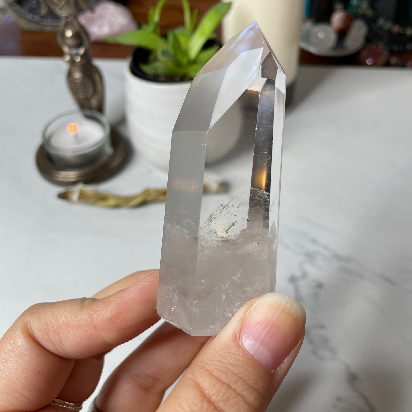 Freya's Haven | Metaphysical & Crystal shop | A close up photo of  a Lemurian seed crystal held in a woman's hand with candles in the background.