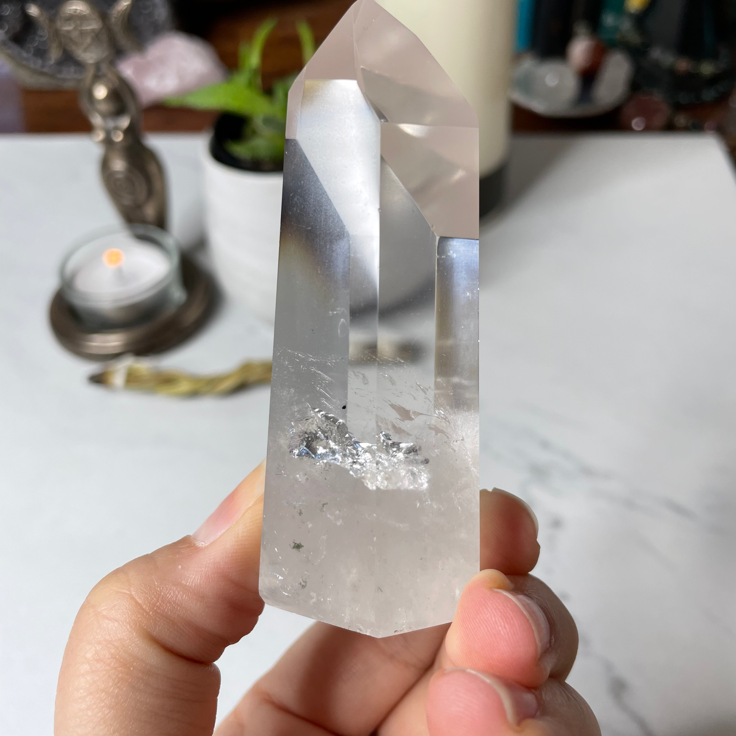 Freya's Haven | Metaphysical & Crystal shop | A close up photo of  a Lemurian seed crystal held in a woman's hand with candles in the background.