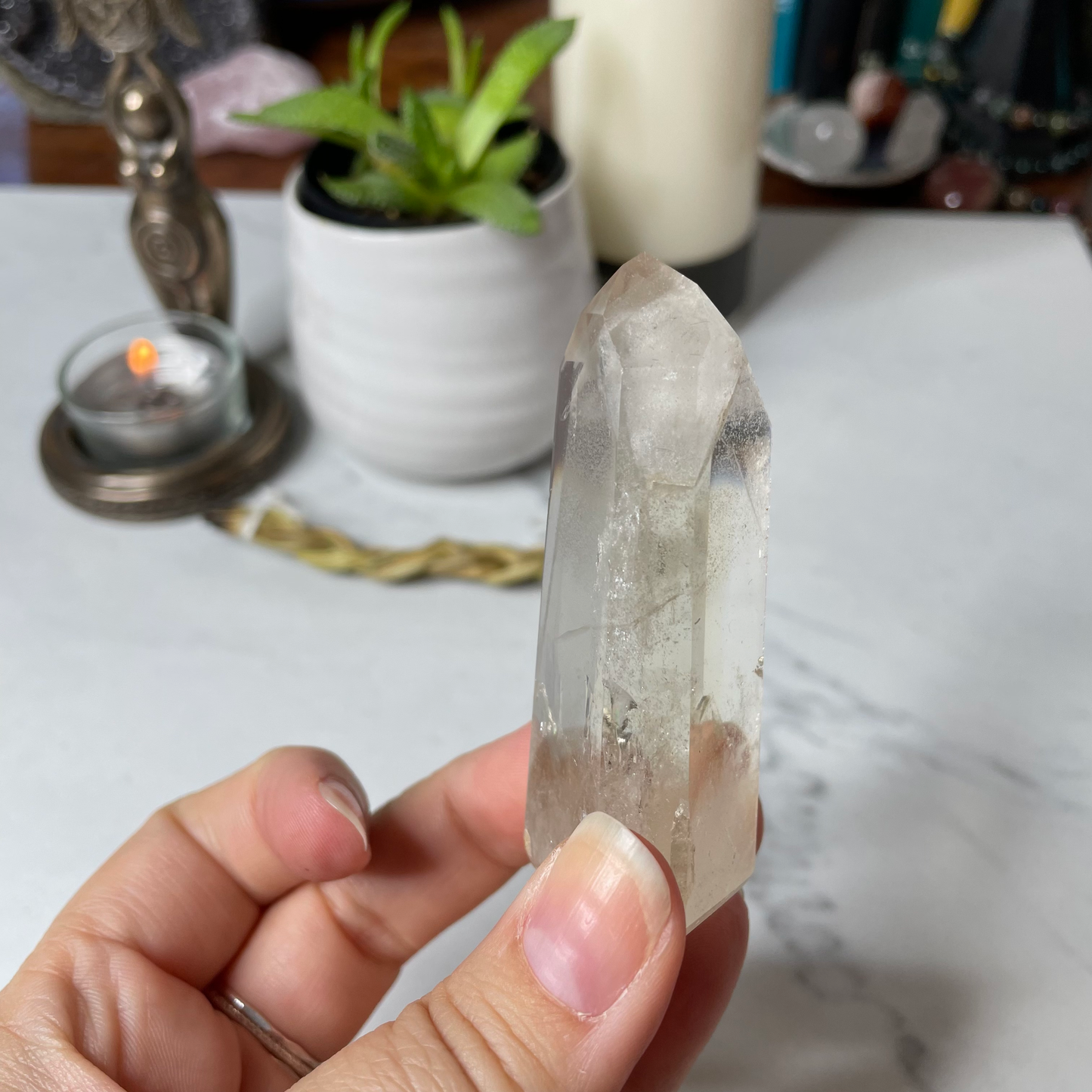 Freya's Haven | Metaphysical & Crystal shop | A close up photo of a Citrine Phantom tower held in a woman's hand with candles in the background.