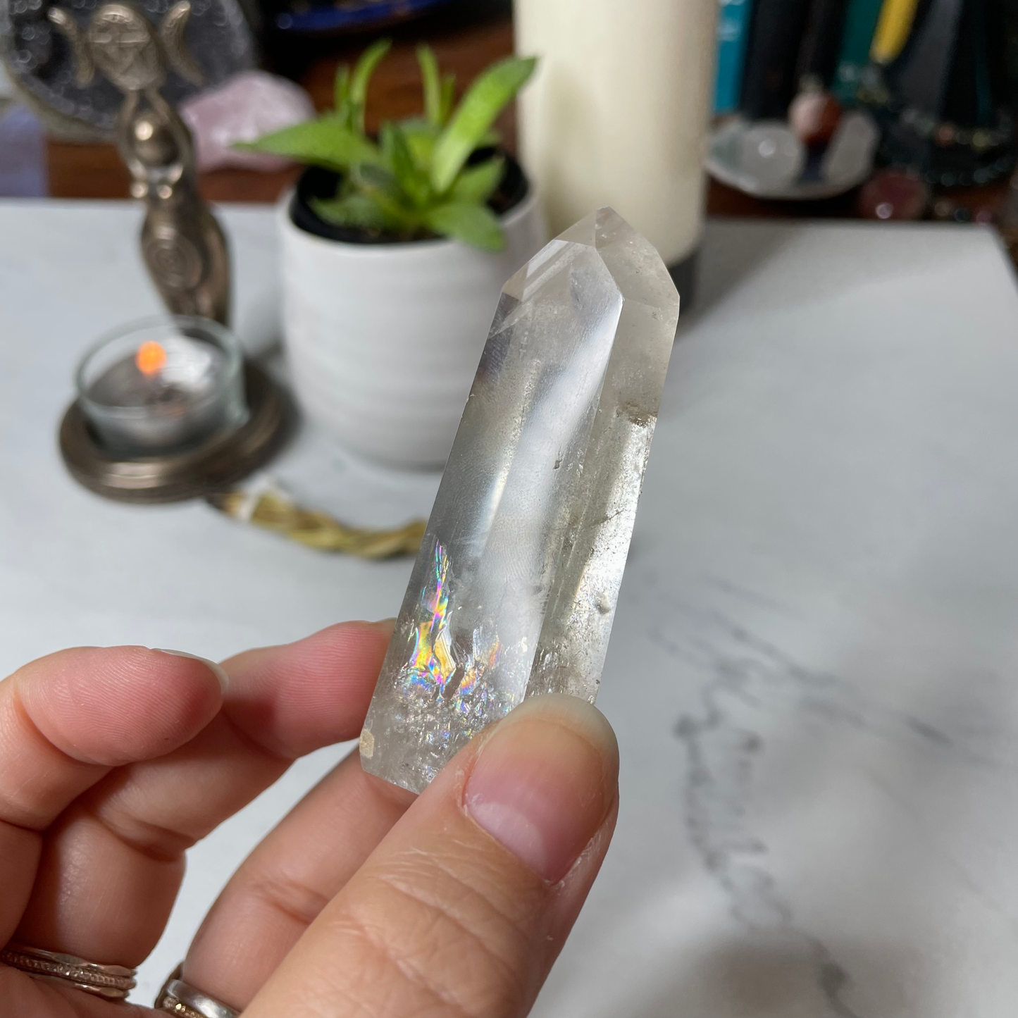 Freya's Haven | Metaphysical & Crystal shop | A close up photo of a Citrine Phantom tower held in a woman's hand with candles in the background.