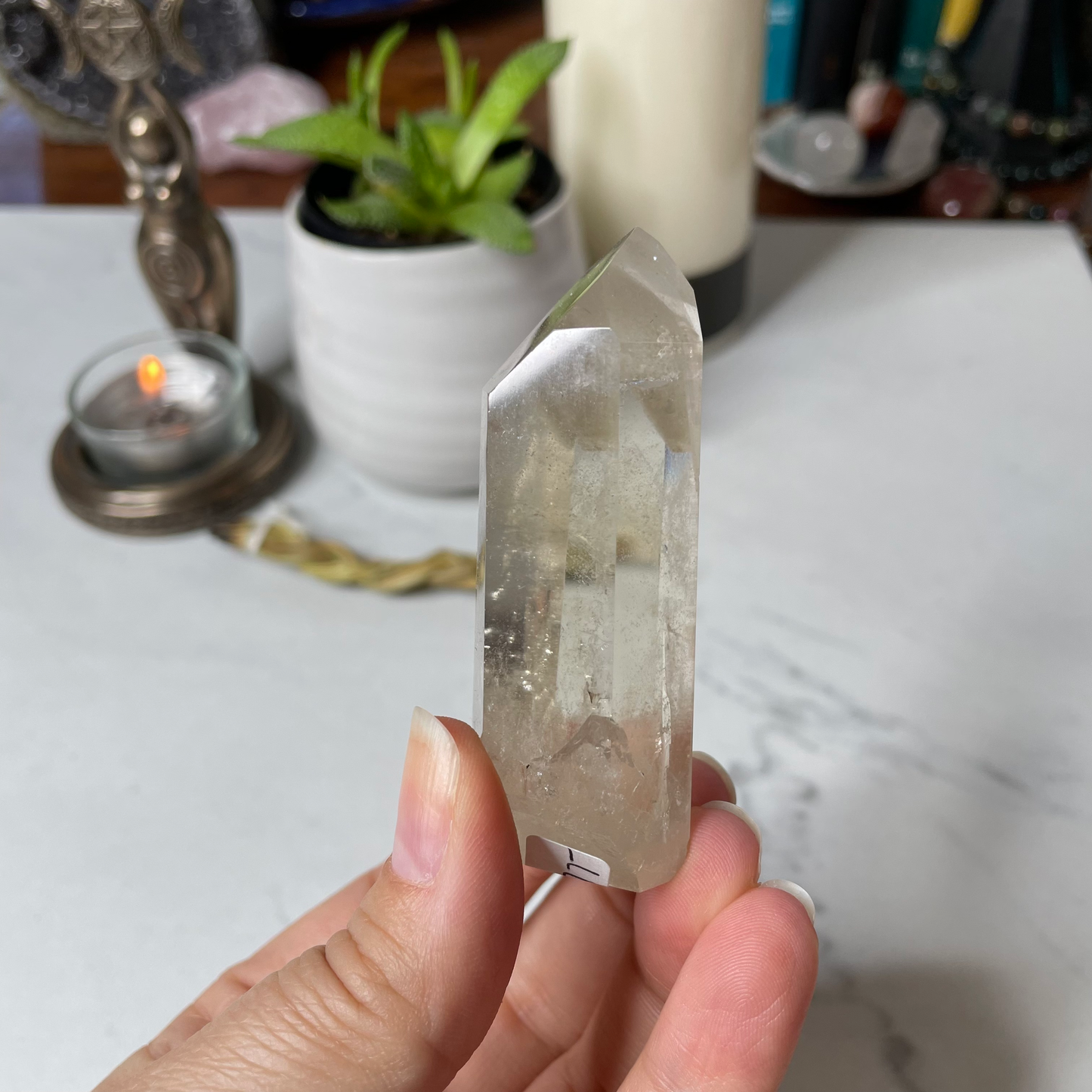 Freya's Haven | Metaphysical & Crystal shop | A close up photo of a Citrine Phantom tower held in a woman's hand with candles in the background.