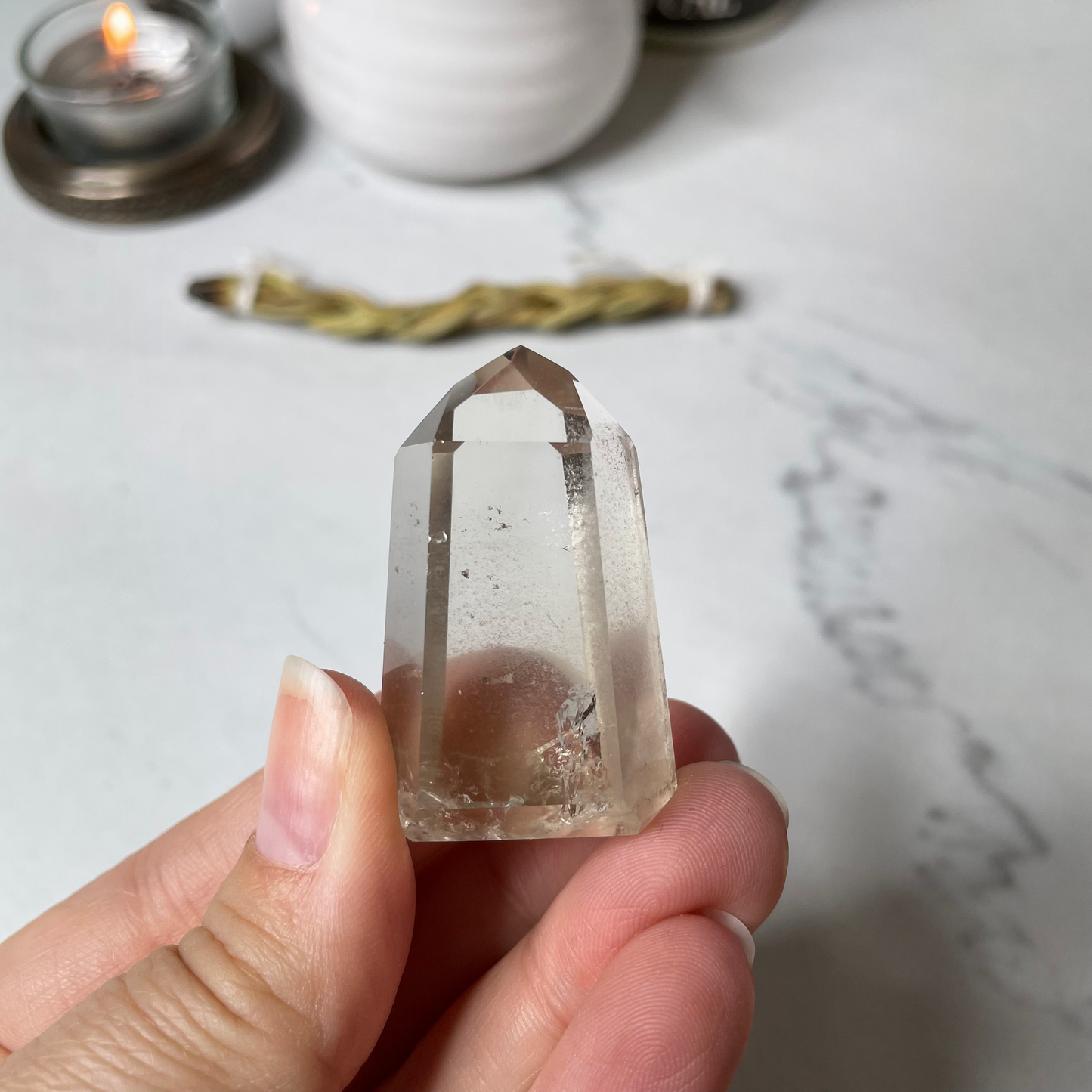 Freya's Haven | Metaphysical & Crystal shop | A close up photo of a Citrine Phantom tower held in a woman's hand with candles in the background.