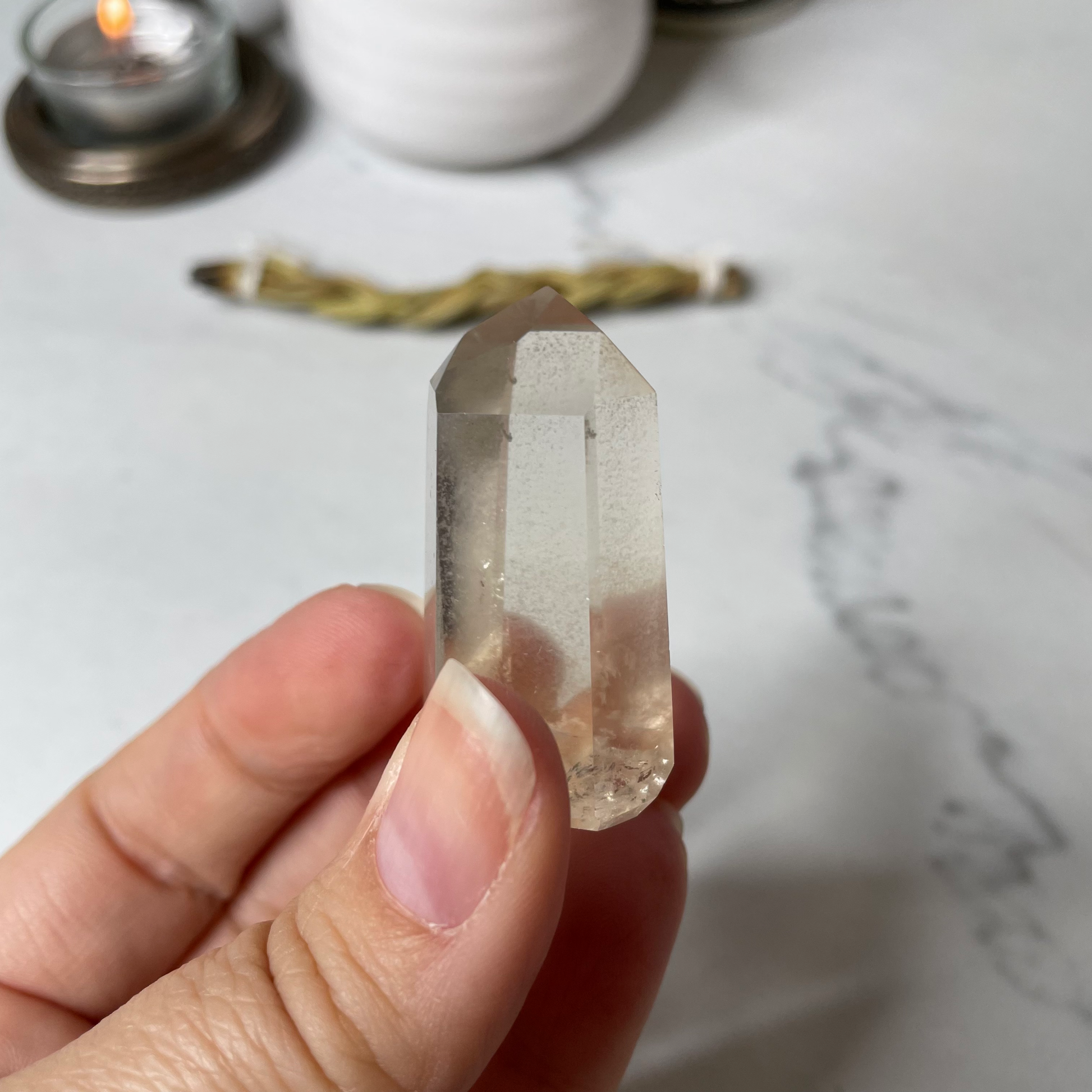 Freya's Haven | Metaphysical & Crystal shop | A close up photo of a Citrine Phantom tower held in a woman's hand with candles in the background.