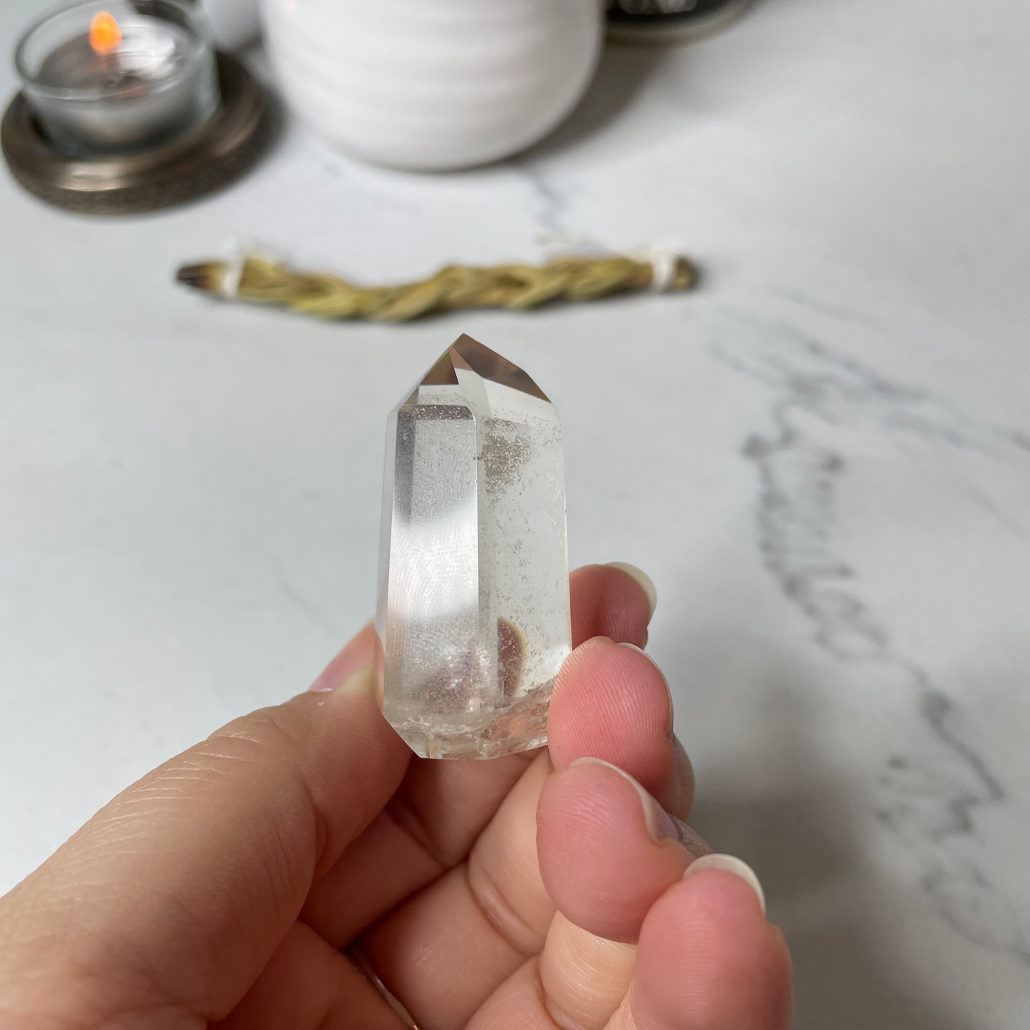 Freya's Haven | Metaphysical & Crystal shop | A close up photo of a Citrine Phantom tower held in a woman's hand with candles in the background.