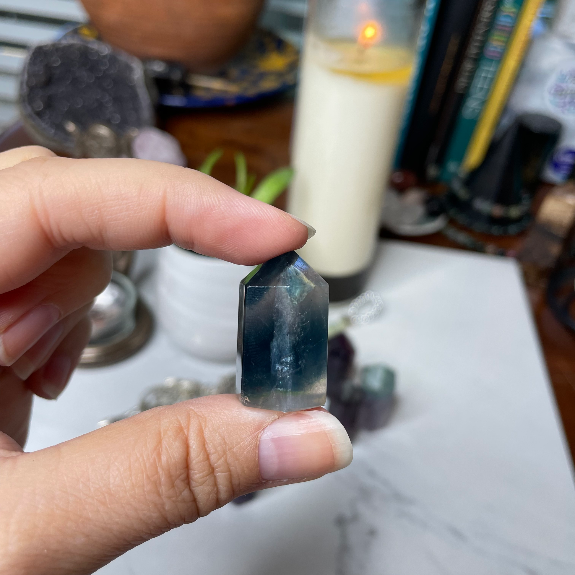 Freya's Haven | Metaphysical & Crystal shop | A close up photo of  a Rainbow Fluorite tower held in a woman's hand with candles in the background.