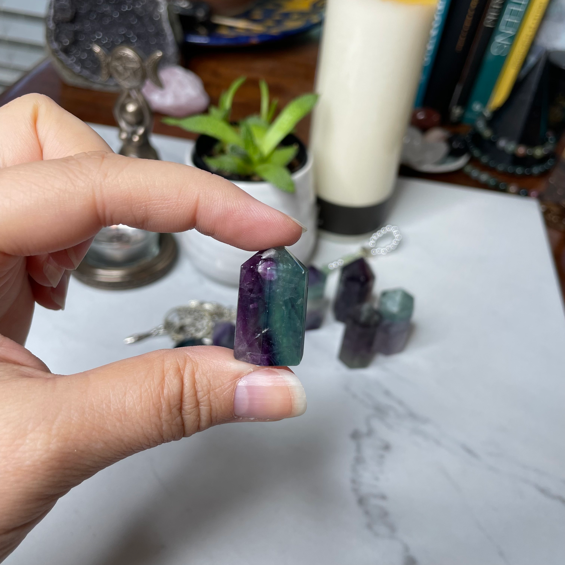 Freya's Haven | Metaphysical & Crystal shop | A close up photo of  a Rainbow Fluorite tower held in a woman's hand with candles in the background.