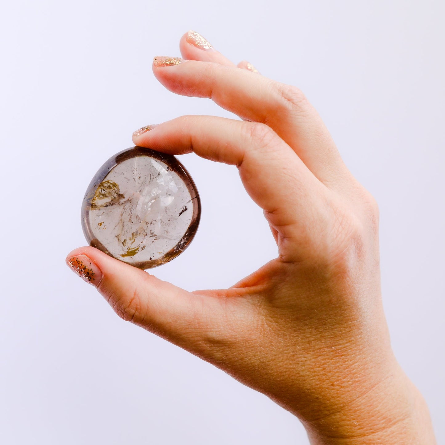 hand holding light gray smoky quartz polished crystal