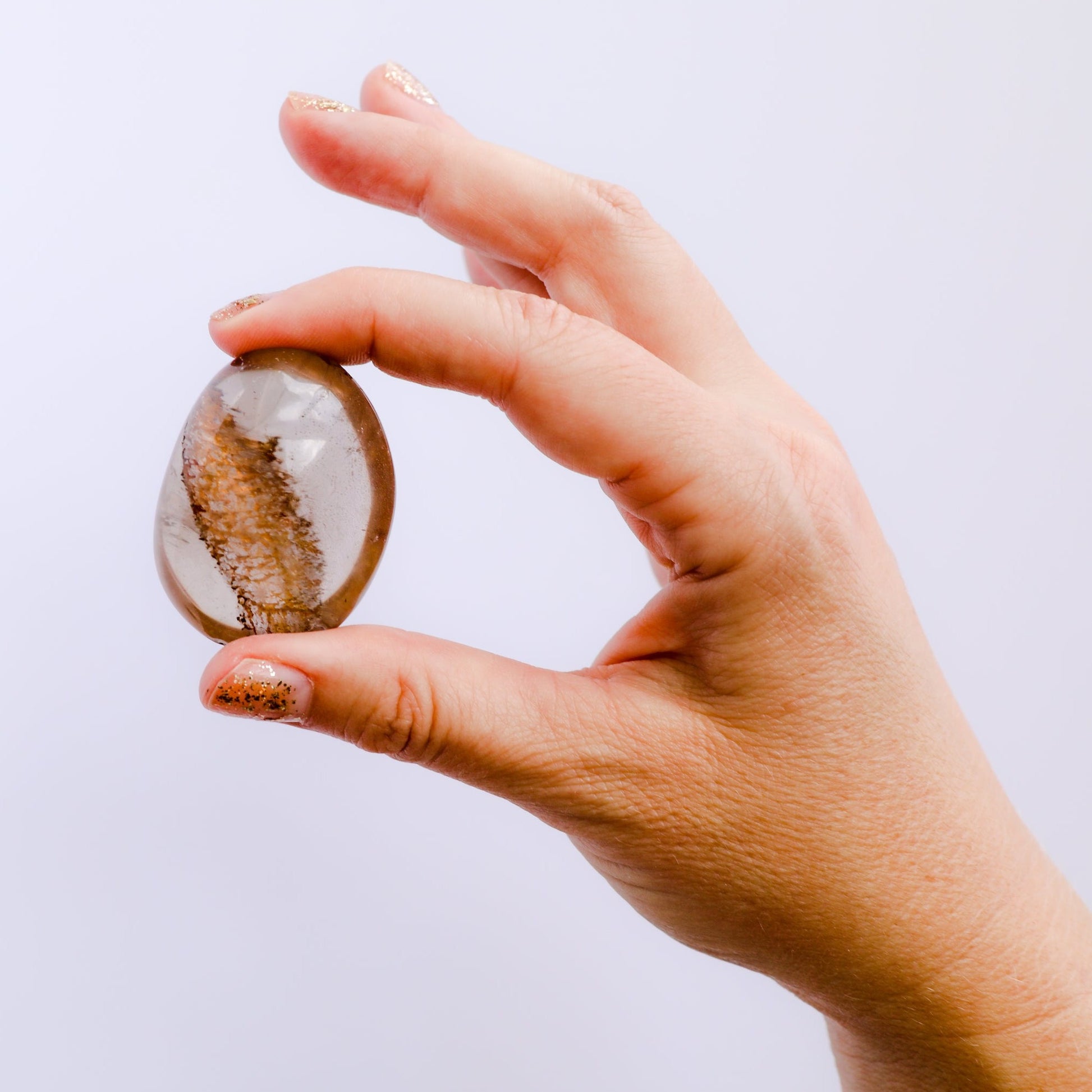 hand holding small smoky gray quartz polished stone
