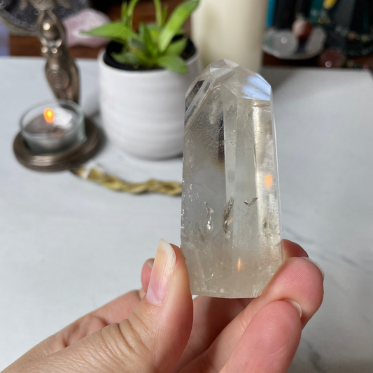 Freya's Haven | Metaphysical & Crystal shop | A close up photo of a Citrine Phantom tower held in a woman's hand with candles in the background.